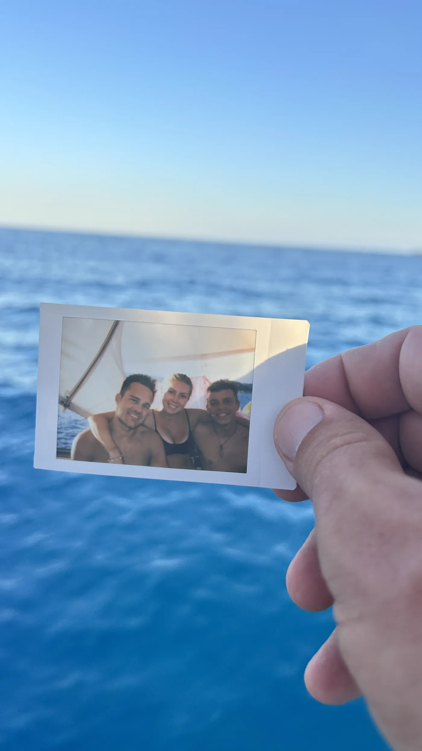 Ein Foto der gemeinsamen Tage, in der Hand gehalten vor dem Meer